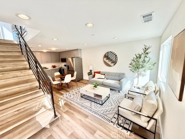 living room featuring stairs, recessed lighting, visible vents, and light wood-type flooring