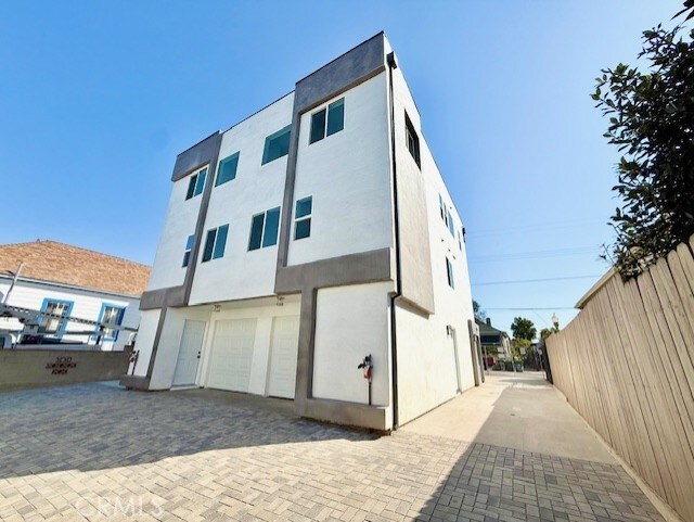 rear view of property featuring an attached garage, fence, and stucco siding