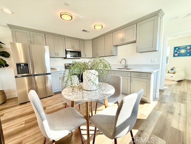 kitchen with appliances with stainless steel finishes, a sink, visible vents, light countertops, and gray cabinetry