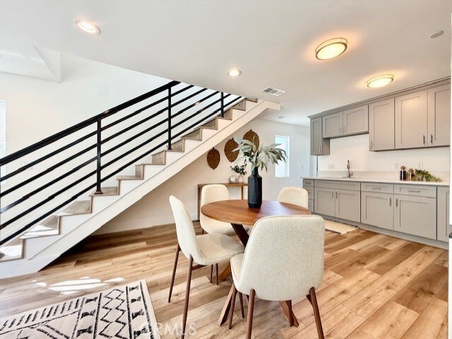 dining space featuring light wood-style floors, recessed lighting, stairs, and visible vents