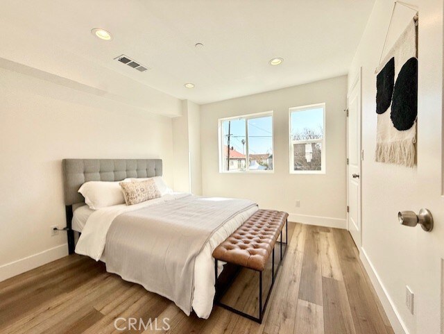 bedroom with visible vents, recessed lighting, baseboards, and wood finished floors