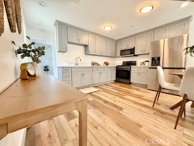 kitchen with light countertops, stainless steel appliances, gray cabinetry, and light wood-style floors