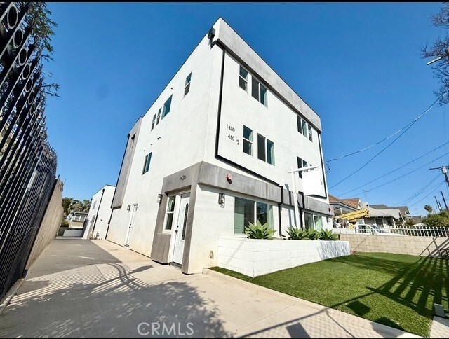 rear view of house featuring fence, stucco siding, and a yard