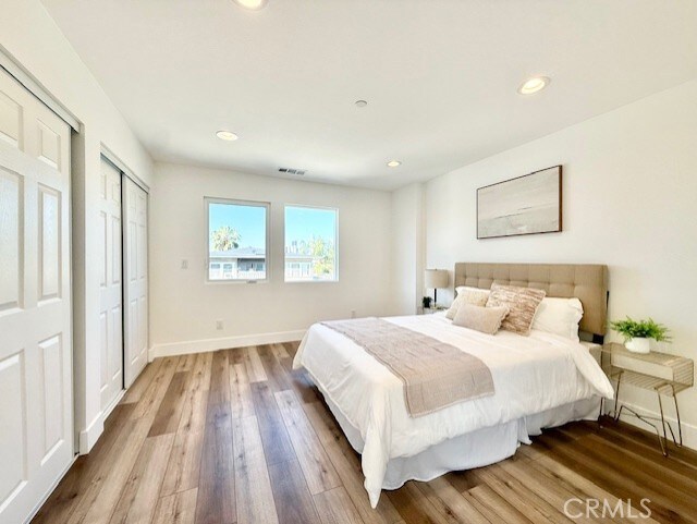 bedroom with recessed lighting, baseboards, visible vents, and wood finished floors