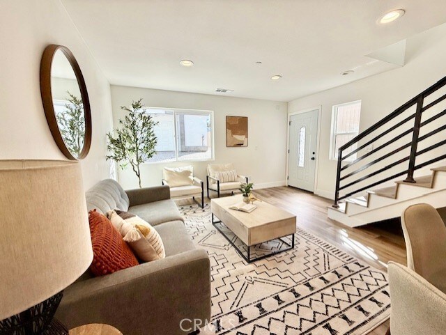 living room with stairs, recessed lighting, baseboards, wood finished floors, and visible vents