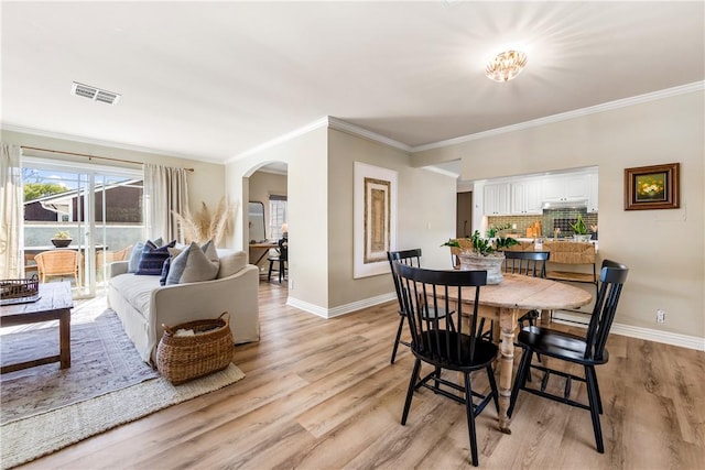 dining room featuring visible vents, arched walkways, baseboards, and light wood-style flooring