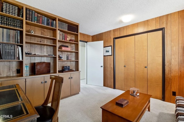 office area featuring wood walls, a textured ceiling, and light colored carpet