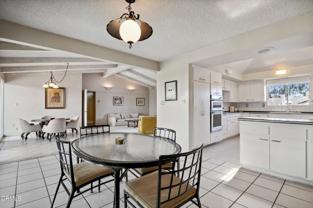 dining space featuring lofted ceiling with beams, light tile patterned floors, and a textured ceiling