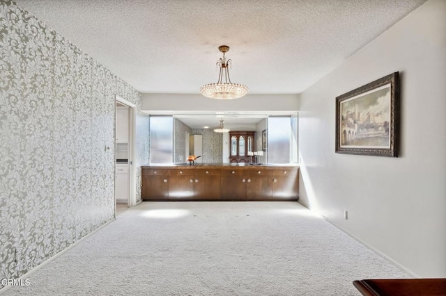 hallway with a textured ceiling, carpet flooring, and wallpapered walls