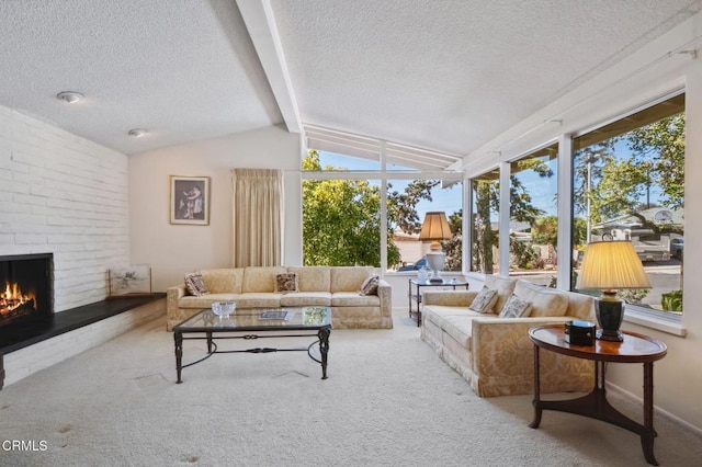 living area featuring lofted ceiling with beams, a textured ceiling, a brick fireplace, and carpet flooring