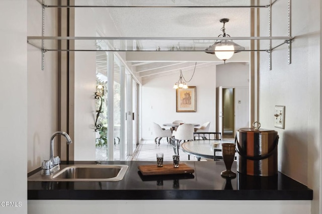 kitchen with a sink, dark countertops, and lofted ceiling with beams