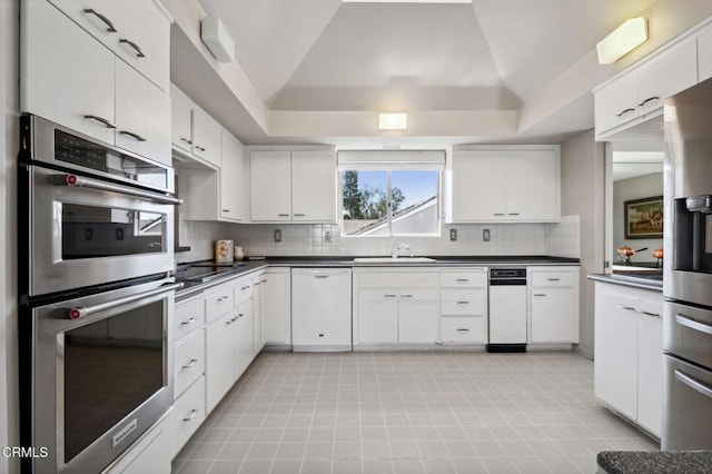 kitchen featuring dark countertops, backsplash, appliances with stainless steel finishes, and a sink