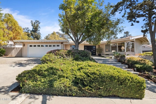 ranch-style house featuring an attached garage, fence, driveway, and stucco siding