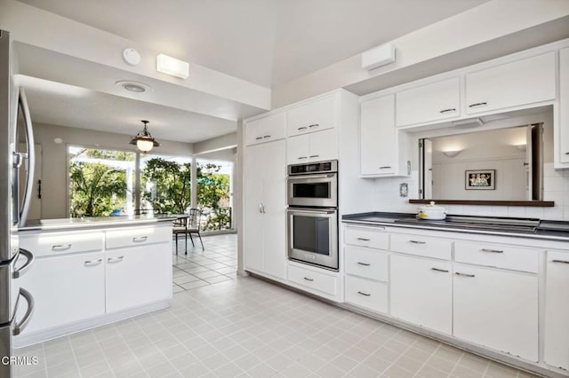 kitchen featuring tasteful backsplash, white cabinets, appliances with stainless steel finishes, and pendant lighting