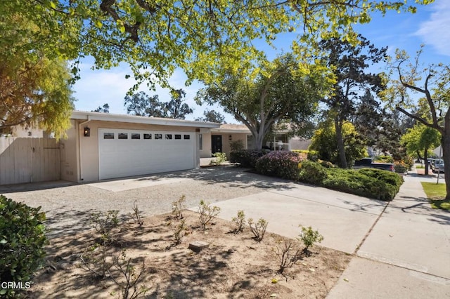 single story home with a garage, stucco siding, driveway, and fence