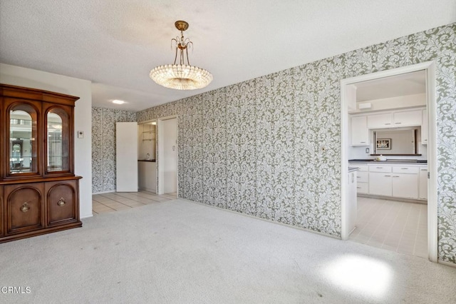 empty room with light carpet, light tile patterned floors, a textured ceiling, and wallpapered walls