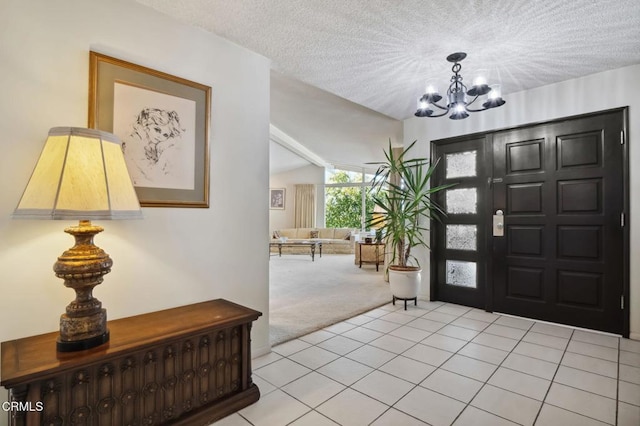 entryway featuring light carpet, a textured ceiling, light tile patterned floors, lofted ceiling, and a chandelier