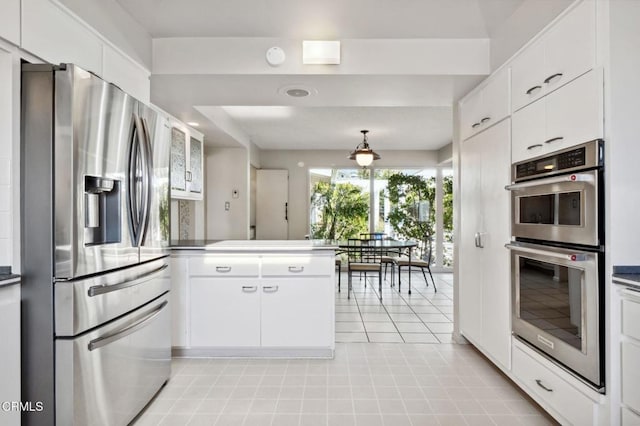 kitchen with a peninsula, white cabinets, light tile patterned flooring, and appliances with stainless steel finishes