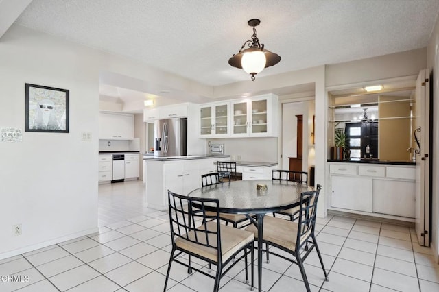 dining room featuring baseboards, a toaster, an inviting chandelier, light tile patterned flooring, and a textured ceiling