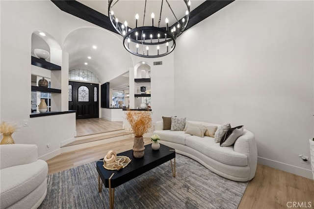 living room with an inviting chandelier, wood finished floors, arched walkways, and visible vents