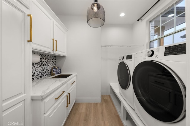 laundry area featuring baseboards, separate washer and dryer, light wood-style floors, cabinet space, and a sink