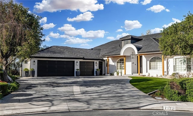 view of front of home featuring brick siding, an attached garage, a tiled roof, and driveway