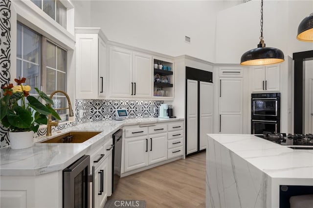 kitchen with black appliances, wine cooler, decorative light fixtures, white cabinetry, and a sink