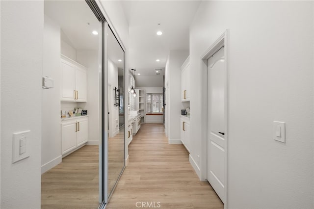 hall featuring light wood-style flooring, recessed lighting, and baseboards