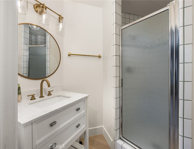 bathroom featuring vanity, wood finished floors, a stall shower, and baseboards