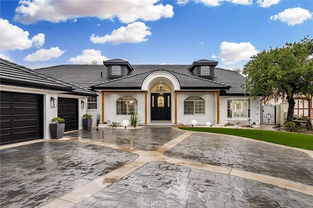 view of front of property with a tiled roof, decorative driveway, and a garage