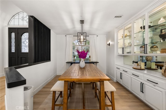 dining area featuring visible vents, light wood-type flooring, and baseboards