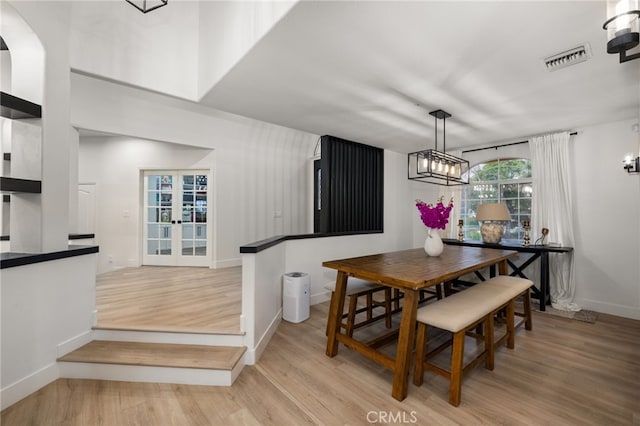 dining space with a notable chandelier, wood finished floors, visible vents, and baseboards