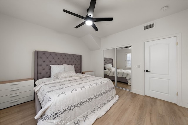 bedroom with a ceiling fan, wood finished floors, visible vents, and a closet