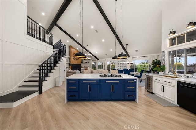 kitchen with blue cabinetry, beamed ceiling, open floor plan, light countertops, and black dishwasher