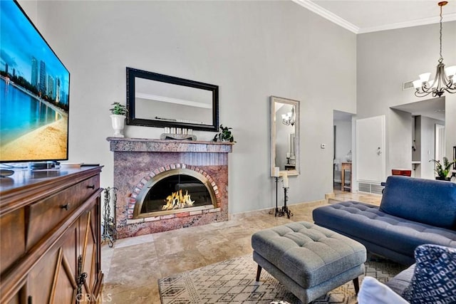 living area with a notable chandelier, a brick fireplace, ornamental molding, and a towering ceiling