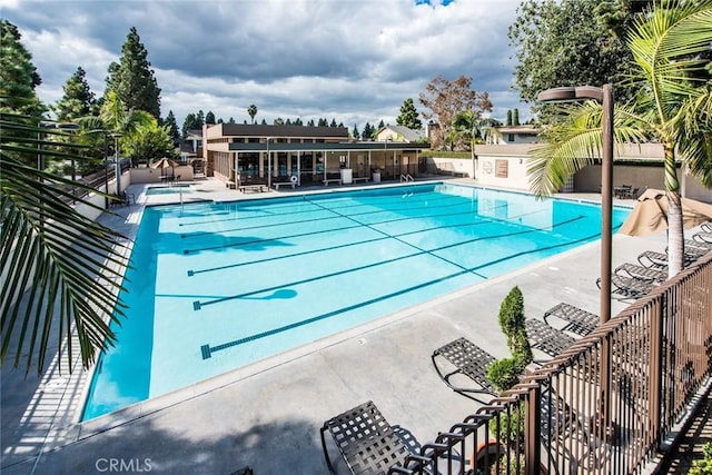 community pool with a patio area and fence