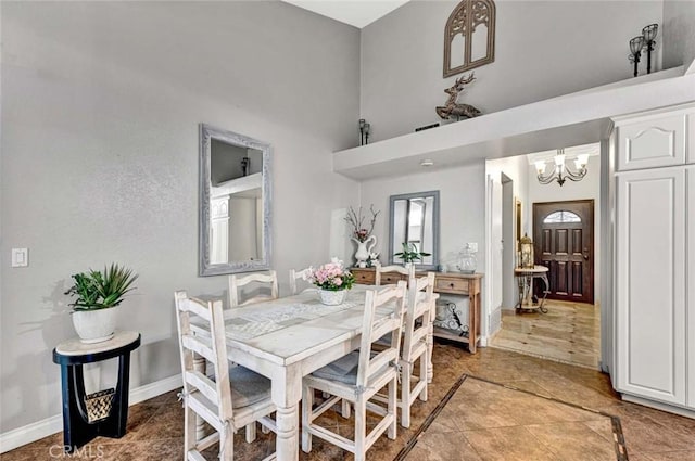 dining room with baseboards, a notable chandelier, and a towering ceiling