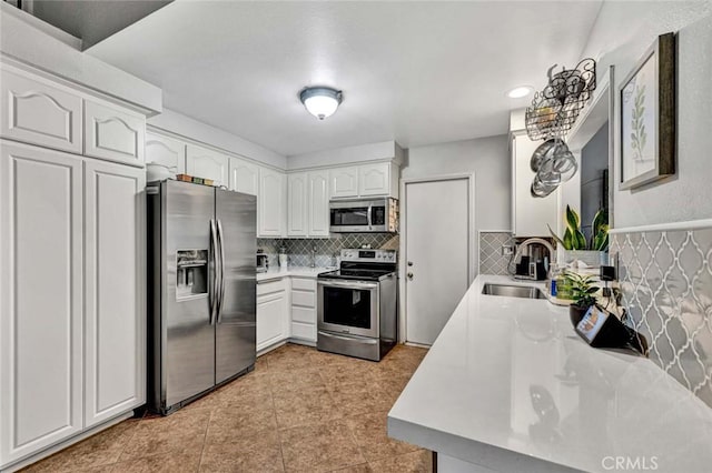 kitchen with tasteful backsplash, light countertops, stainless steel appliances, white cabinetry, and a sink