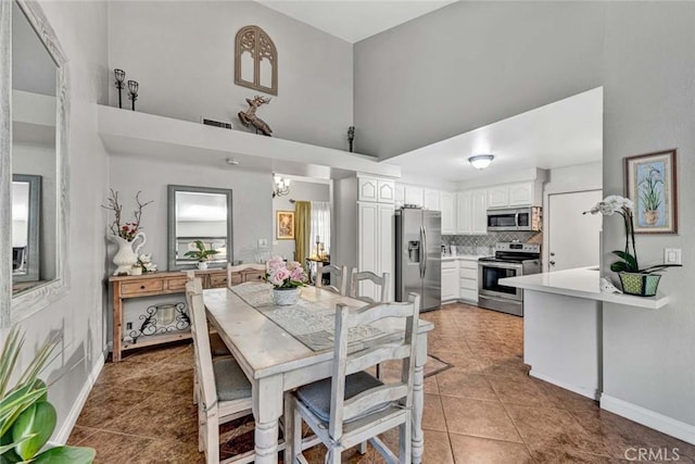 dining room with light tile patterned flooring, visible vents, a high ceiling, and baseboards