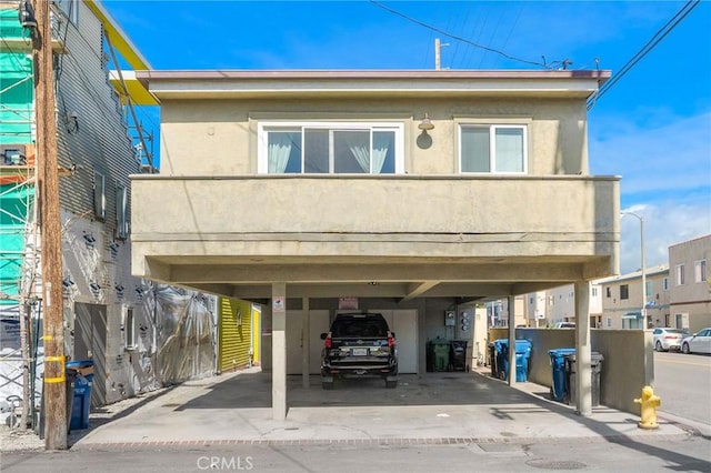 view of front facade featuring stucco siding, a carport, and a balcony