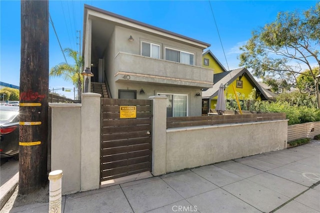 view of front of house with a fenced front yard, stucco siding, and a gate