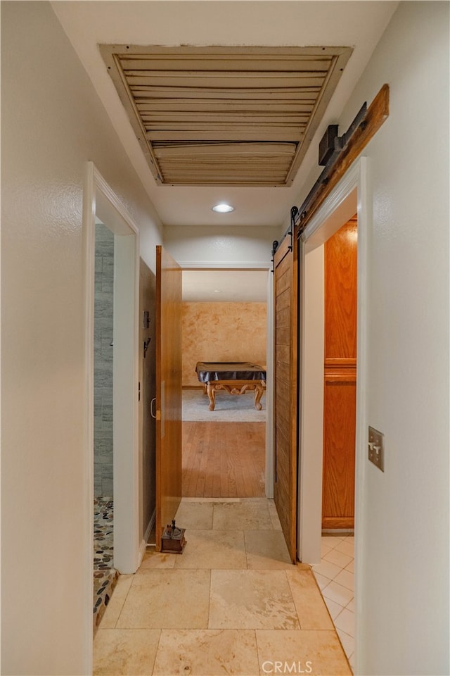 hall featuring stone tile flooring, visible vents, and a barn door