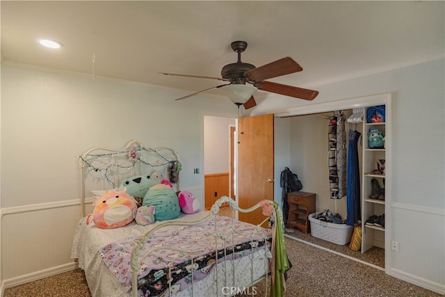 carpeted bedroom featuring a closet, a wainscoted wall, a ceiling fan, and ornamental molding