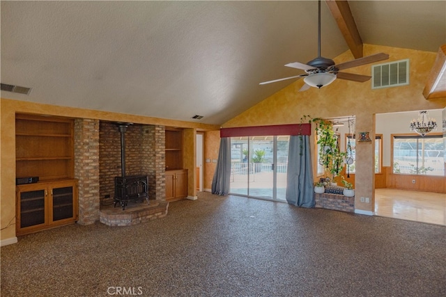 unfurnished living room with visible vents, built in shelves, beamed ceiling, and a wood stove