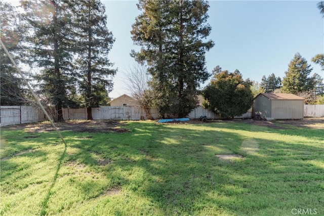 view of yard featuring a storage unit, an outdoor structure, and a fenced backyard