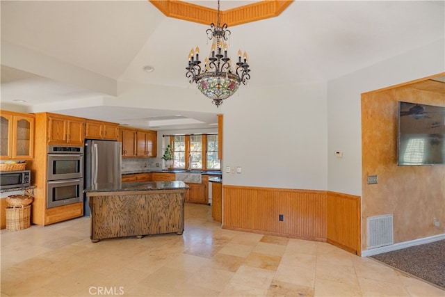 kitchen featuring a wainscoted wall, brown cabinetry, visible vents, and appliances with stainless steel finishes