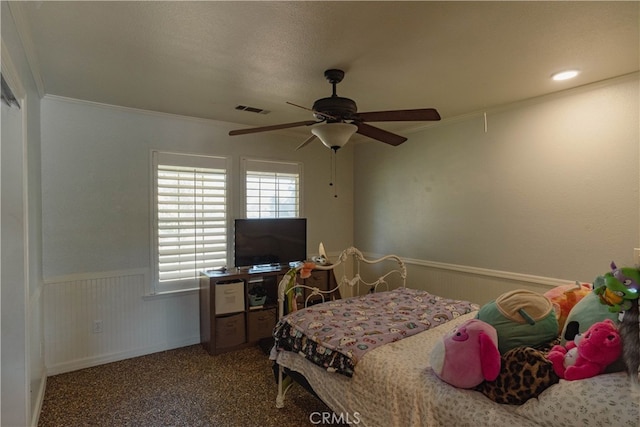 bedroom with visible vents, ceiling fan, carpet, a wainscoted wall, and ornamental molding