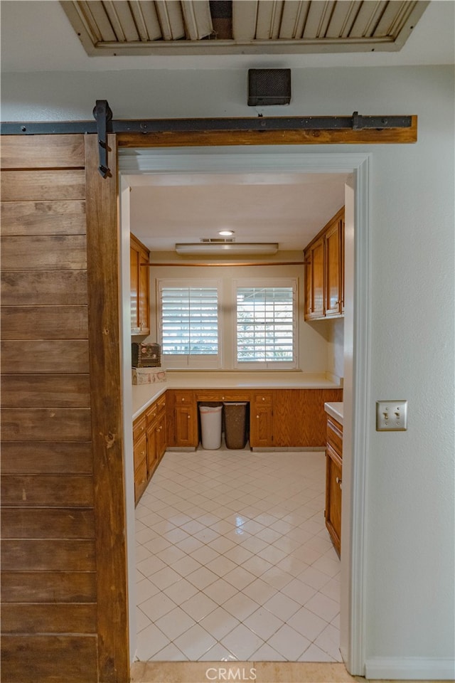 kitchen with a barn door, brown cabinets, and light countertops