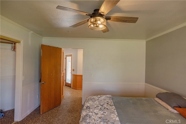 bedroom featuring crown molding, a ceiling fan, a wainscoted wall, and carpet floors