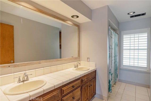 full bath with double vanity, visible vents, baseboards, and a sink